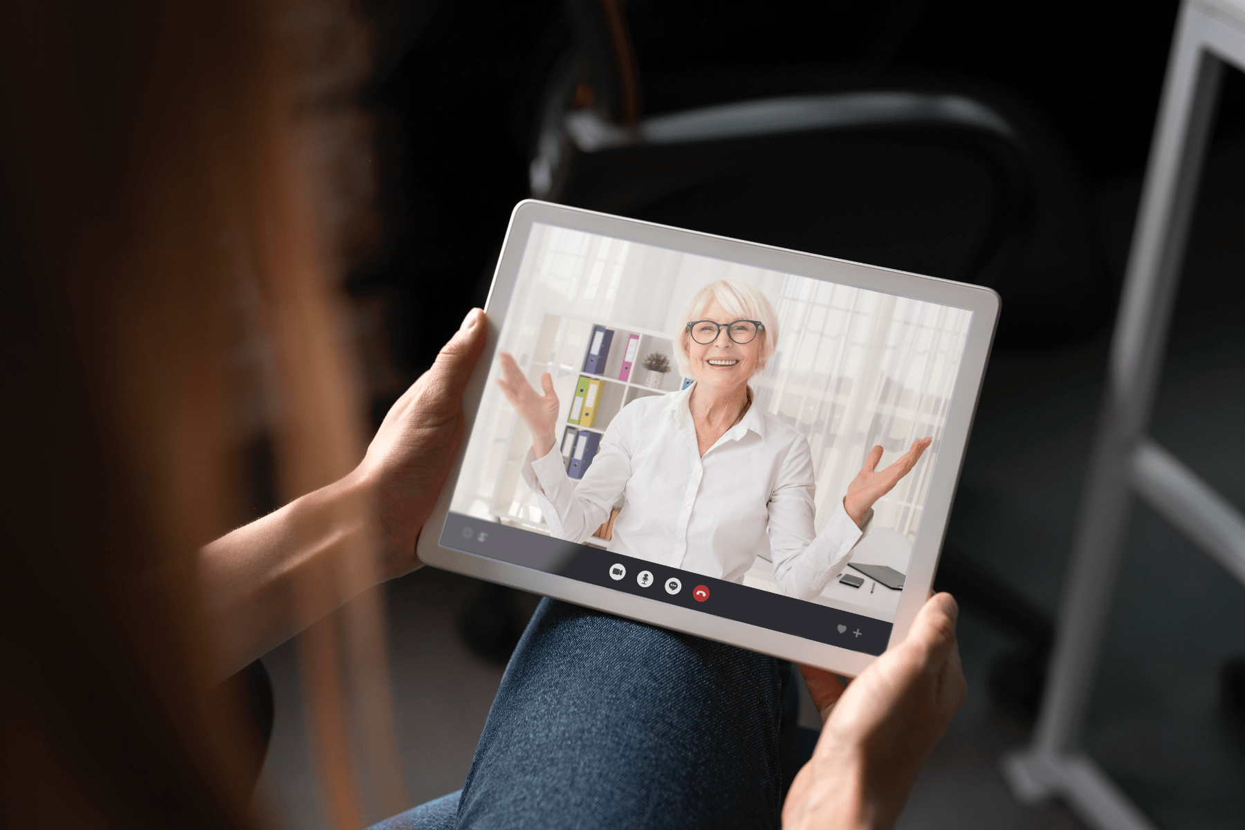 Patient hält ein Tablet in der Hand und befindet sich gerade mit einer Ärztin in der Videosprechstunde